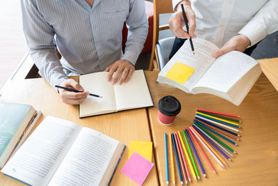 High angle view of people discussing book on table