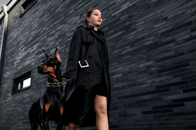 Portrait of young woman standing against wall