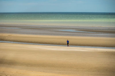Rear view of woman running on sand at beach