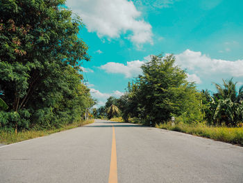 Empty road amidst trees against sky