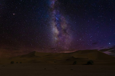 Scenic view of snowcapped mountains against star field