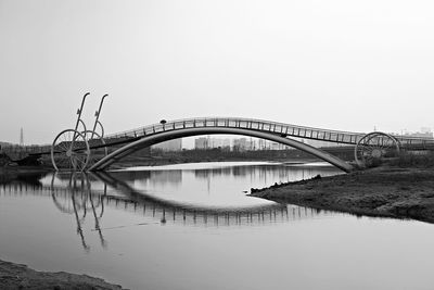 Bridge over calm river against clear sky