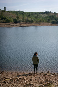 Rear view of man standing by lake