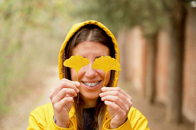 Smiling woman holding leaves in front of eyes