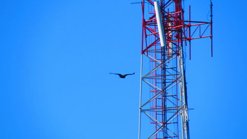 Low angle view of crane against clear blue sky