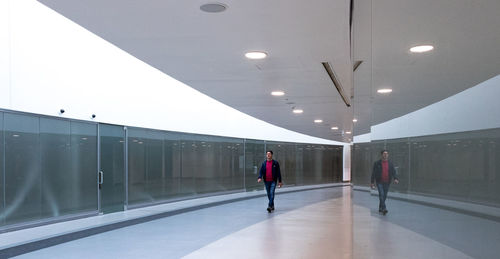 Rear view of people walking on illuminated corridor