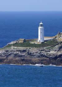 Lighthouse by sea against sky