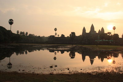Silhouette of temple at lake during sunset
