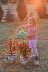 Girl watering plants while standing on grass