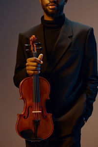 Midsection of man playing violin against black background