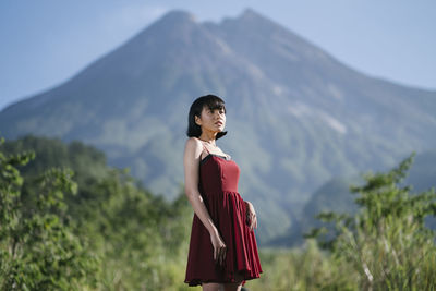 Low angle view of woman standing against mountain 