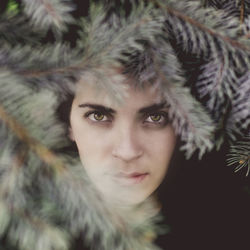 Close-up portrait of young woman by tree in winter