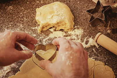 A person making heart-shaped cookies using a cookie cutter