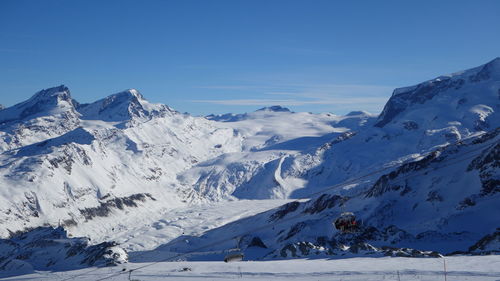 Scenic view of snowcapped mountains against blue sky