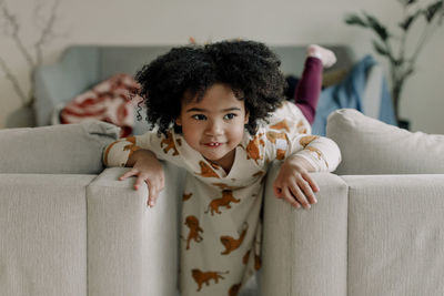 Playful girl leaning on armchairs in living room