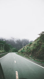 Road amidst trees against clear sky