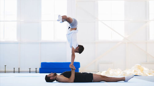 Instructor with teenage boy practicing gymnastics in club