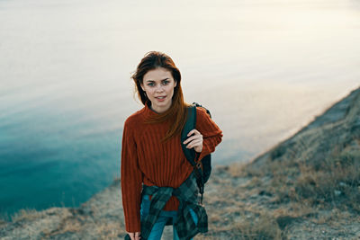 Portrait of young woman standing against sea