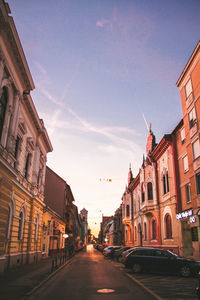 Road amidst buildings in city against sky