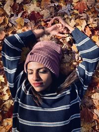 High angle portrait of woman lying on autumn leaves