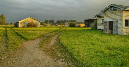 Houses on field against cloudy sky