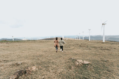 Rear view of couple running on field