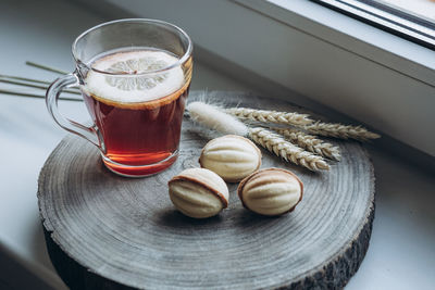 Still life cup of hot tea with lemon and cake nuts on a wooden stand