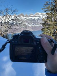 Man photographing on snowcapped mountain against sky