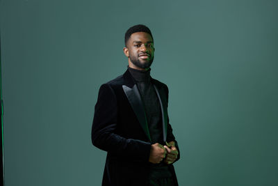 Portrait of businessman standing against black background