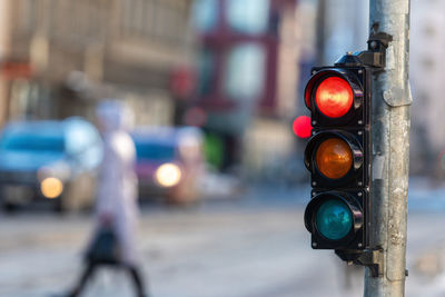 Close-up of small traffic semaphore with red light against the backdrop of the city traffic