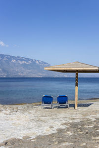 Chair on beach against clear blue sky