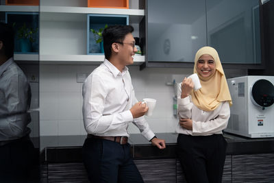 Business people having coffee while standing in office cafeteria