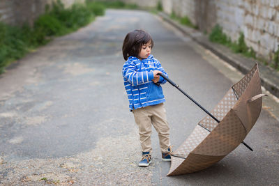 Little handsome baby boy playing with umbrella outdoor