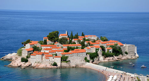 Buildings by sea against clear blue sky