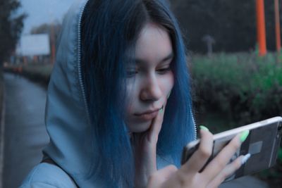Close-up of young woman using mobile phone while standing outdoors