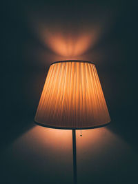 Close-up of illuminated lamp against wall at home