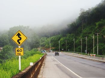 Sign by road in foggy weather