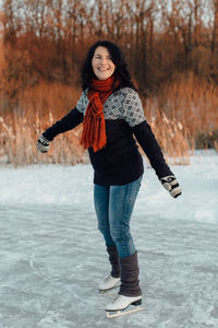 Smiling woman ice-skating on frozen lake