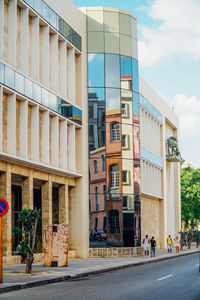 Buildings by road against sky in city