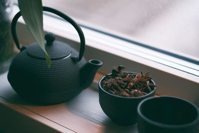 Close-up of spices in cup with teapot on table