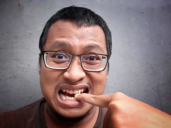 Portrait of man wearing eyeglasses against wall