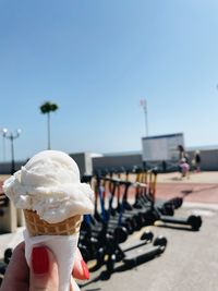 Hand holding ice cream against clear sky