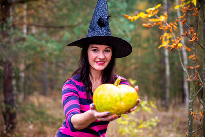 Halloween witch with a magic pumpkin in a dark forest.