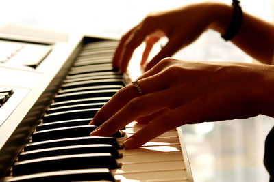 Cropped hands of woman playing piano
