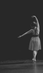 Full length of a female ballerina against black background