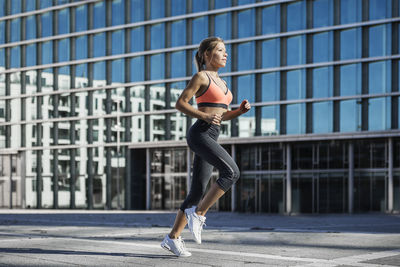 Woman in sports clothing running in city