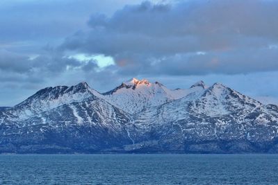 Scenic view of snowcapped mountains by sea against sky