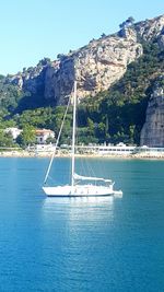 Sailboat sailing on sea against clear blue sky