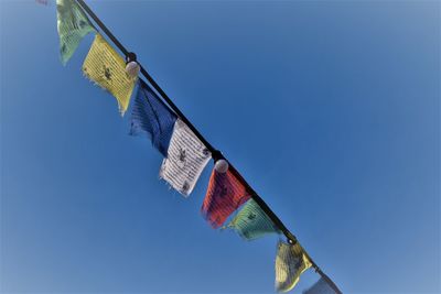 Low angle view of flags hanging against blue sky