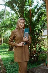 Portrait of young woman using mobile phone while standing outdoors